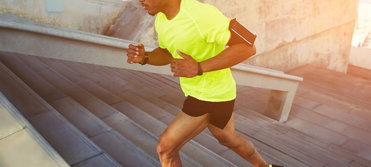 A man wearing a bright yellow shirt and socks running up some steps
