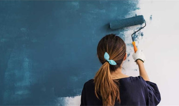 Woman painting wall blue with a roller