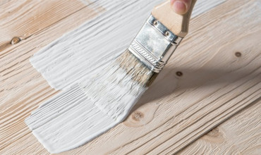 White paint being applied to wood with paint brush