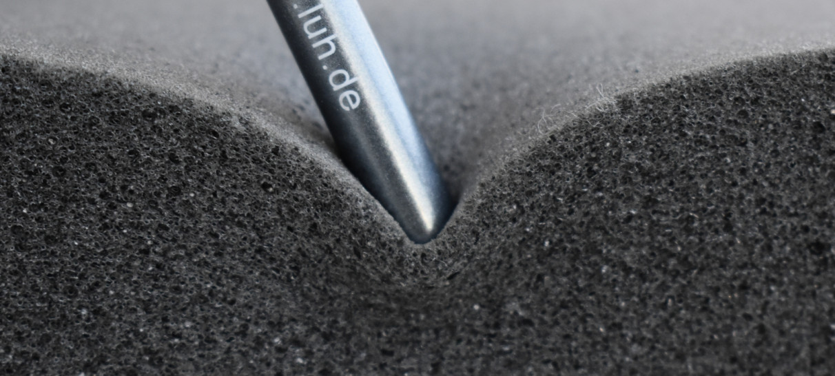 Graphite pencil pushing into foam