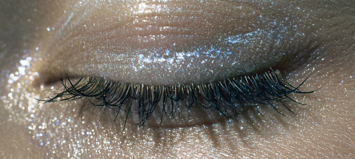 A very up close image of an eye with silver eyeshadow