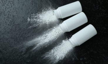 Three bottles of white powder are spread out on a table as if comparing talc to other replacement options