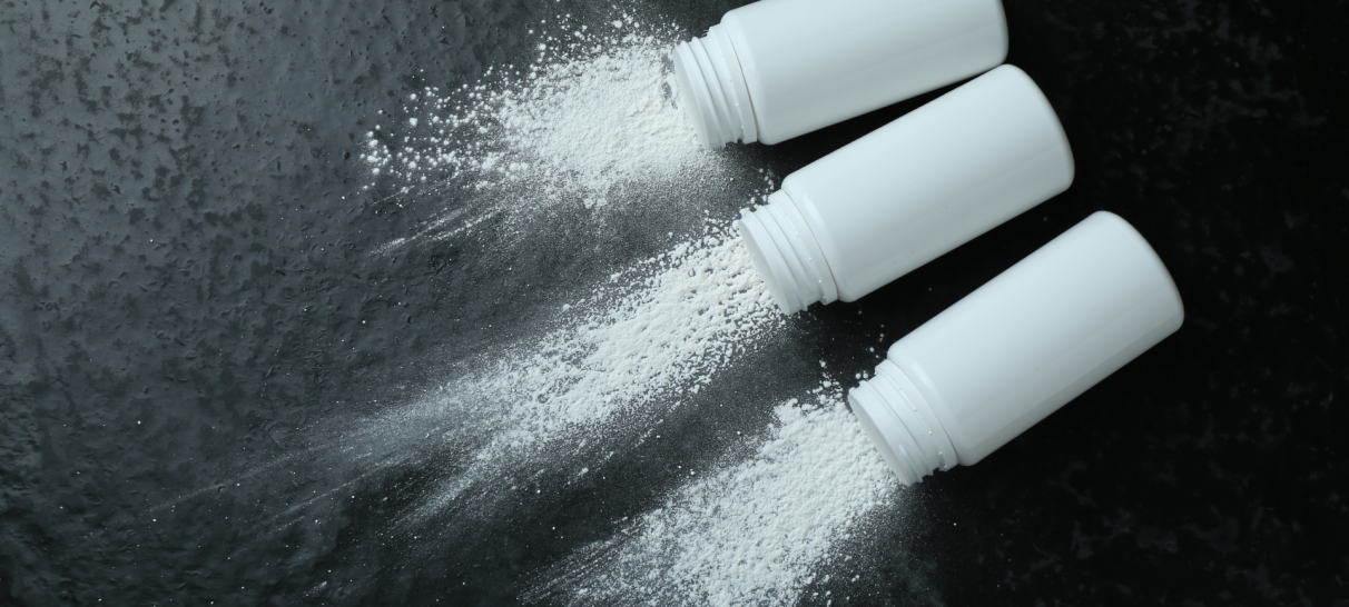 Three bottles of white powder are spread out on a table as if comparing talc to other replacement options
