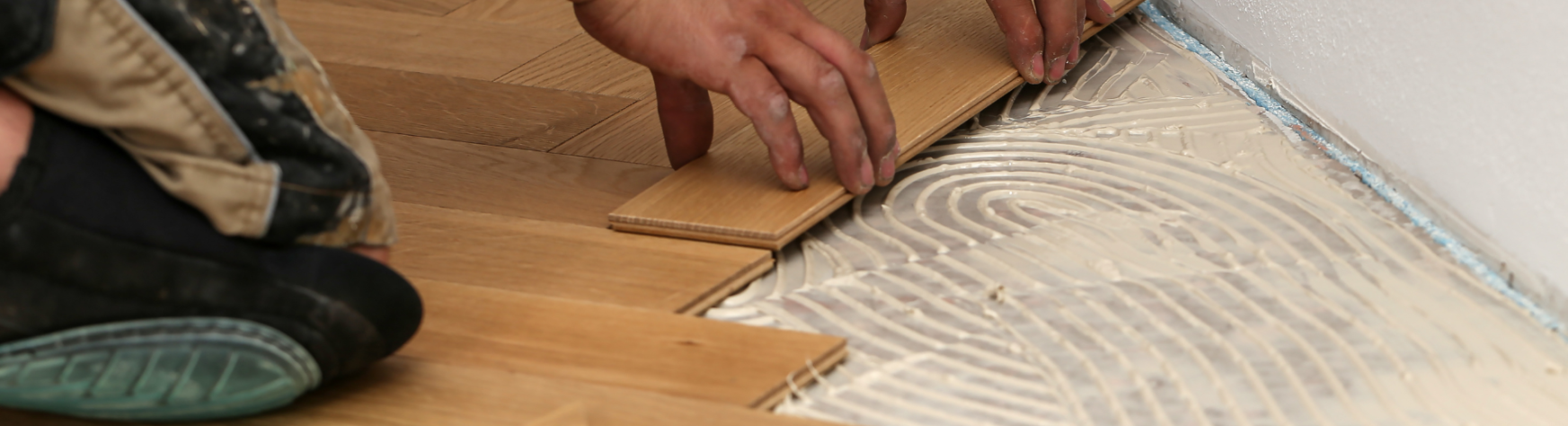 A man laying parquet flooring, a main application of AQUANEX